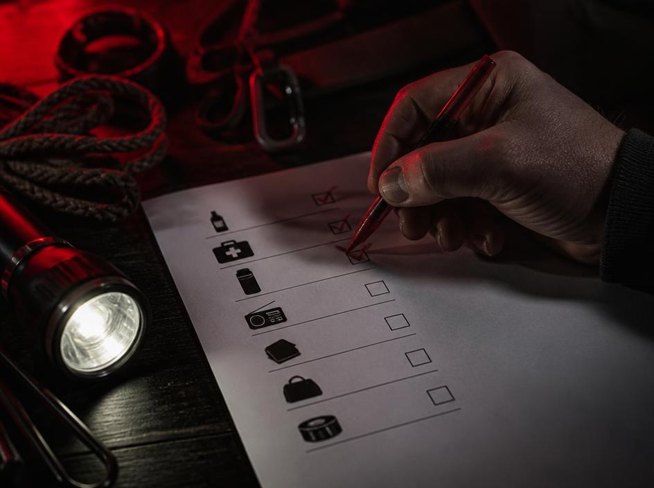 Mano marcando un checklist de preparación con linterna